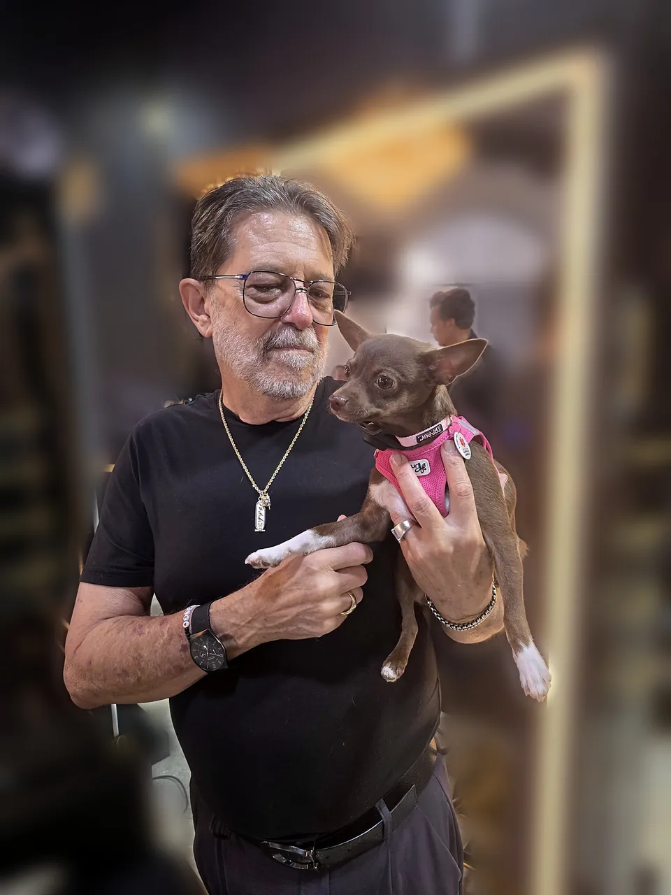 Demi in her pink harness, safe in Jimmy's arms at the salon